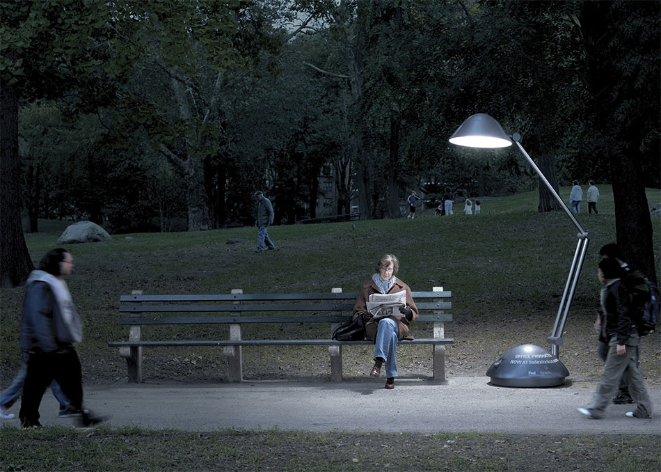 Stona lampa osvetljava ženu za vreme čitanja na klupi u parku - reklamiranje web sajta fedexkinkos com